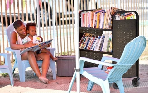 a woman reads a book to a child at a pop-up reading room