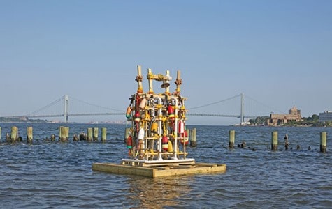 a compilation of buoys and bells float on the water against the backdrop of the verrazano-narrows bridge