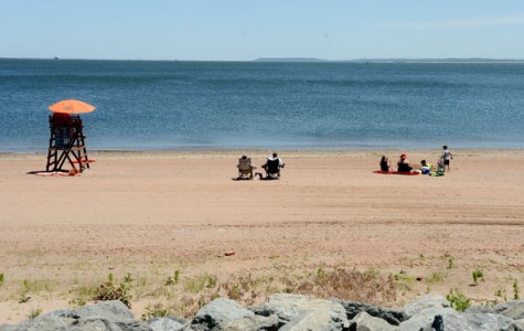 Beachgoers lounge in their beach chairs at a beach where a lifeguard is on duty