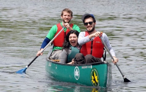 three people use a park ranger canoe on a lake