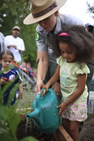 Ranger instructing child about plant watering